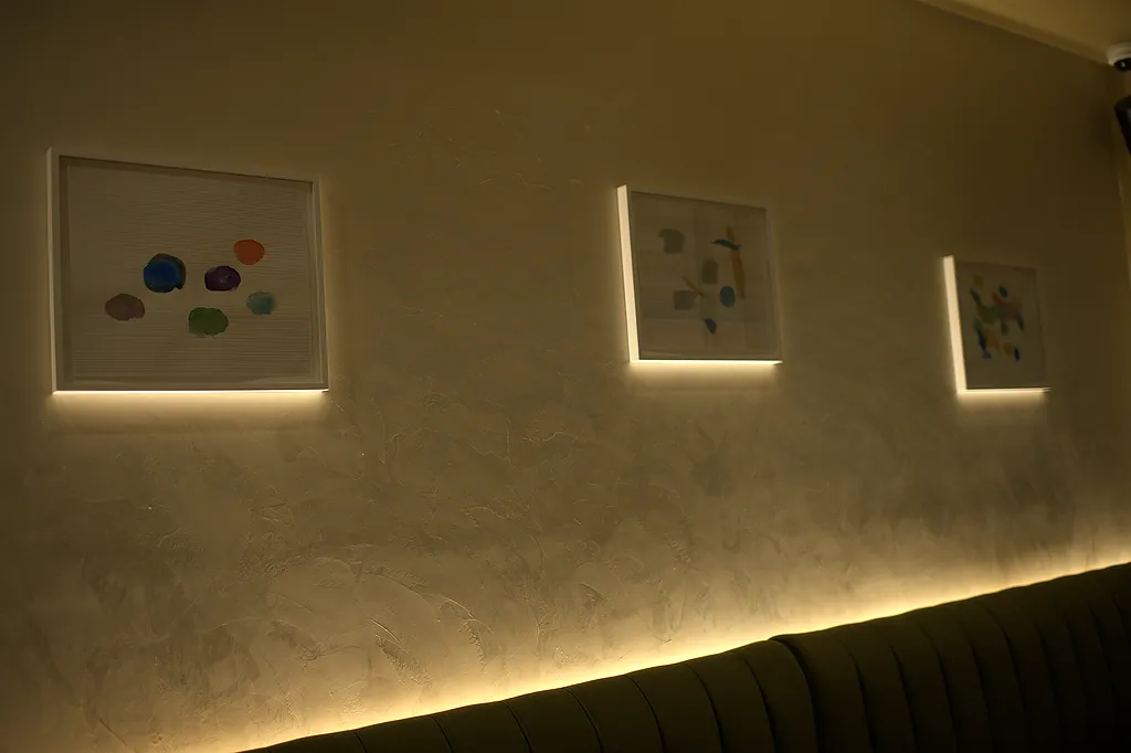 Framed works hung along the dining room wall