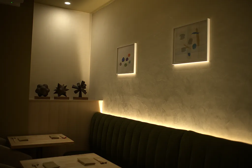 Green velvet banquettes below framed artwork