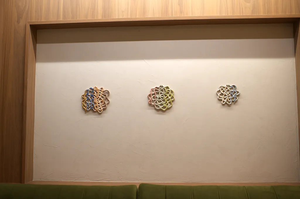 Three ceramic wall works above the banquette