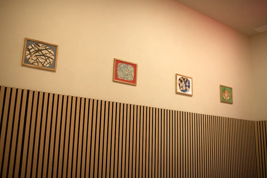 Slatted oak wall hung with three small framed works